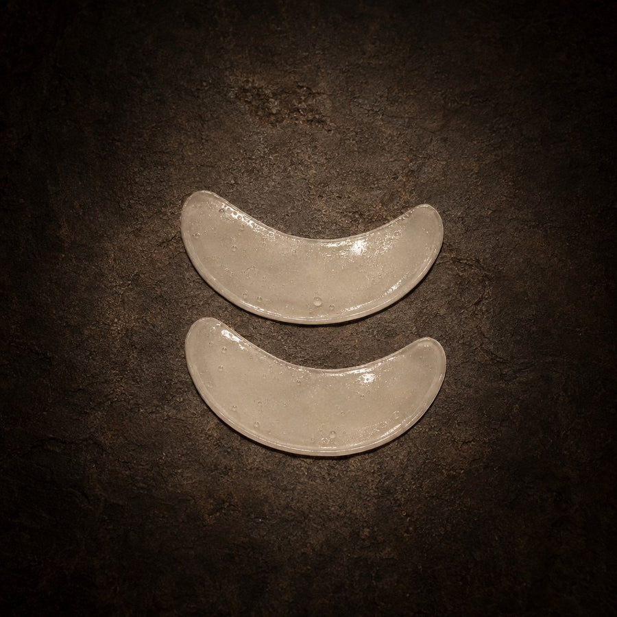 A pair of clear Ice under-eye patches on dark stone
