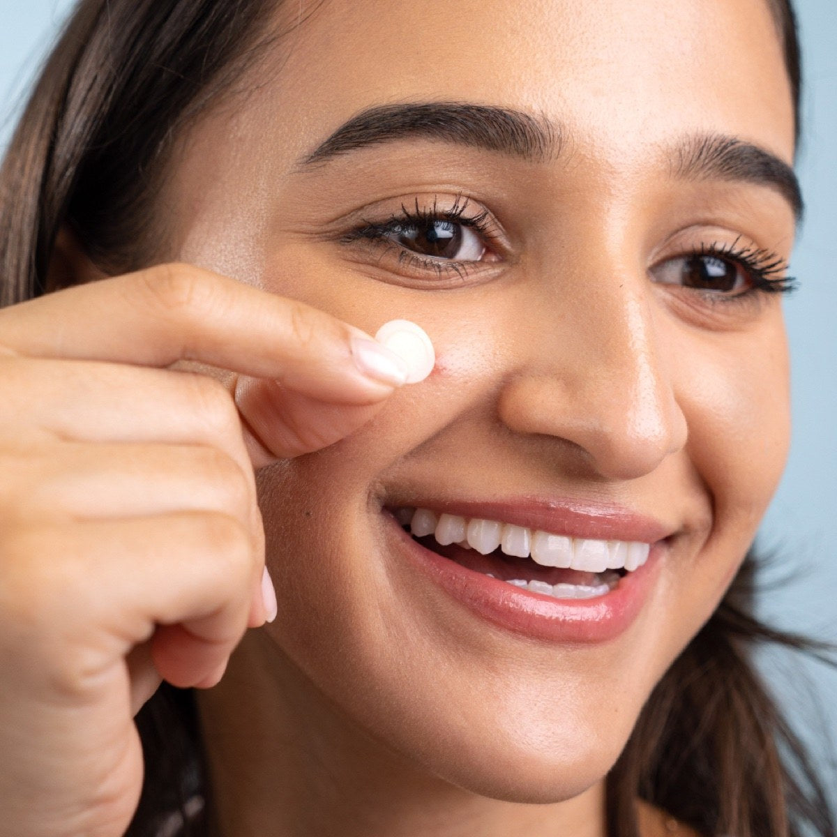 Smiling woman pressing an Iron patch onto her cheek